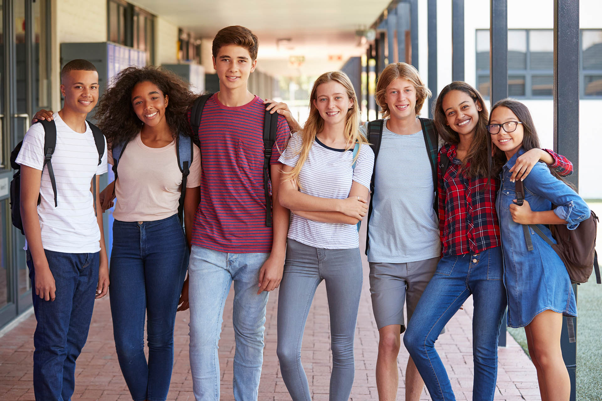Teenage classmates standing in high school hallway
