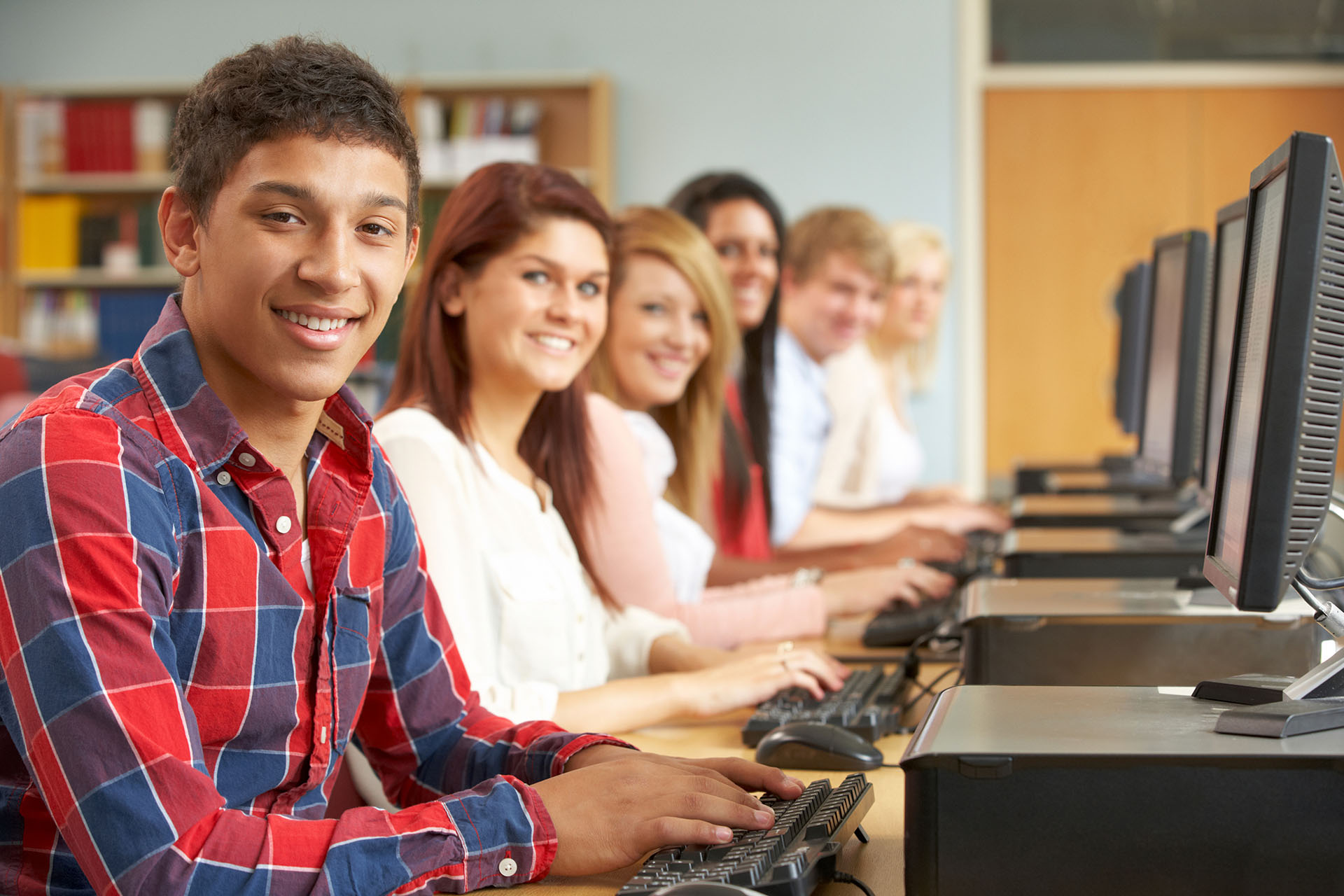 Students lined up and typing on keyboards with computer monitors.